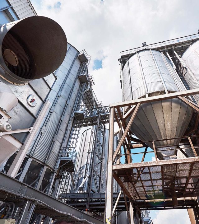 Agricultural Silos. Building Exterior. Storage and drying of grains, wheat, corn, soy, sunflower against the blue sky with white clouds.